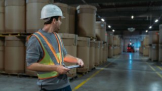 Radnici u skladištu nose interaktivne upozoravajuće prsluke kompanije Linde Material Handling u skladištu bez svetla